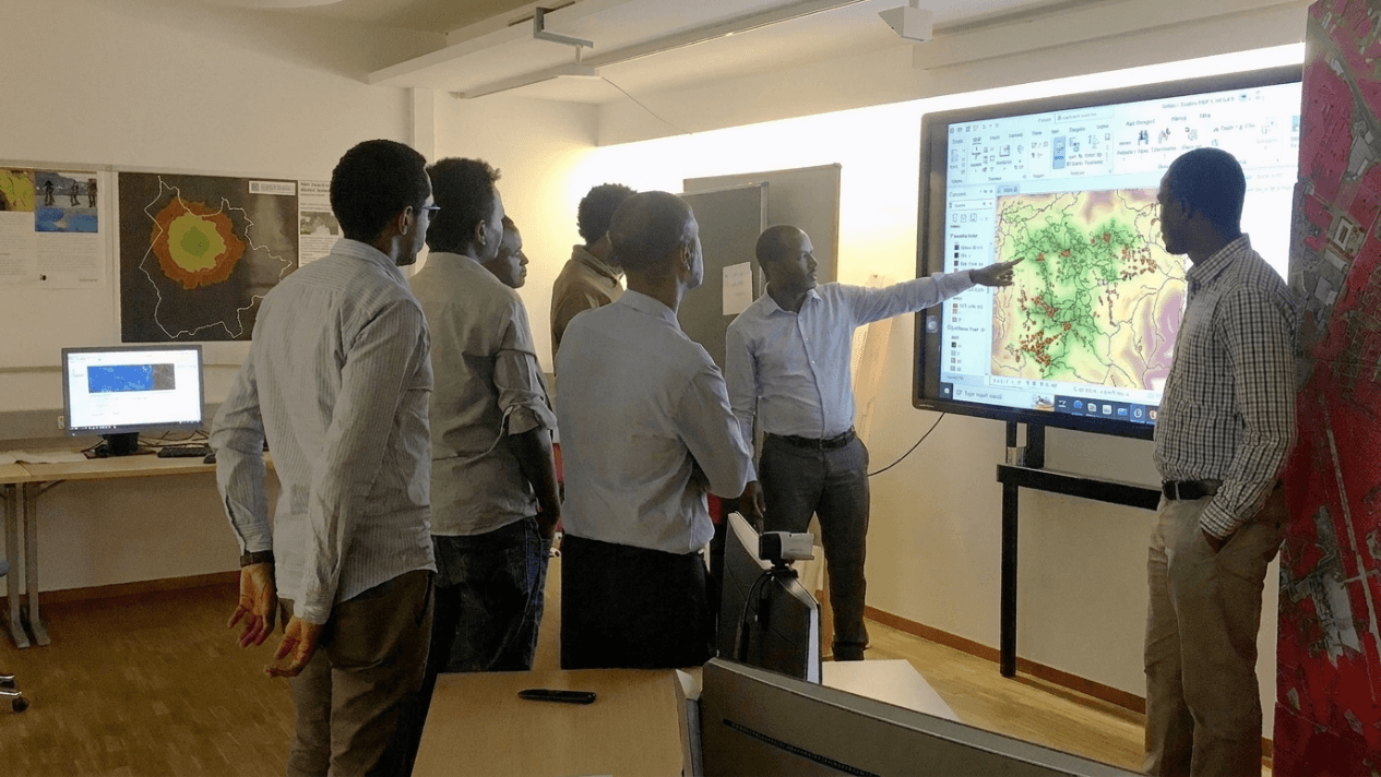Trainer pointing at a map on a screen during a GIS workshop