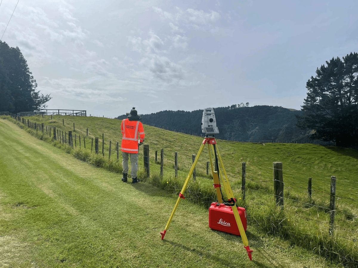Surveyor with a total station on a hillside field